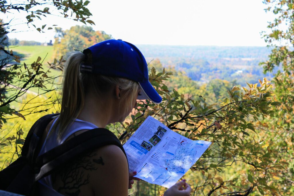 Eine junge Frau, die auf einen Plan schaut; im Hintergrund der Kellerwald
