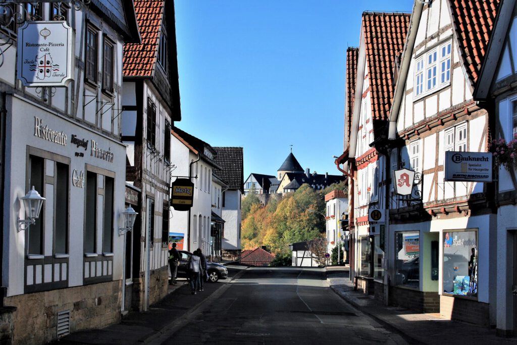 Stadtzentrum von Waldeck; links und rechts stehen an einer kleinen Straße mehrere Fachwerkhäuser; im Hintergrund ist das Waldecker Schloss zu sehen